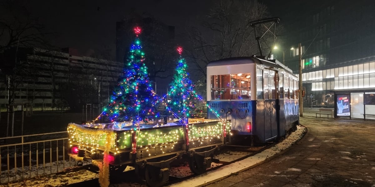 Zabytkowy tramwaj z choinkami świątecznymi na lorze transportowej, zdjęcie archiwalne.