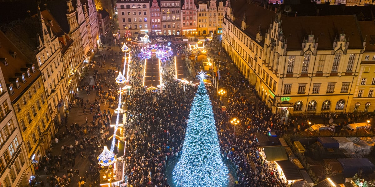 Tłum ludzi zgromadzonych wokół rozświetlonej choinki na Wrocławskim Rynku