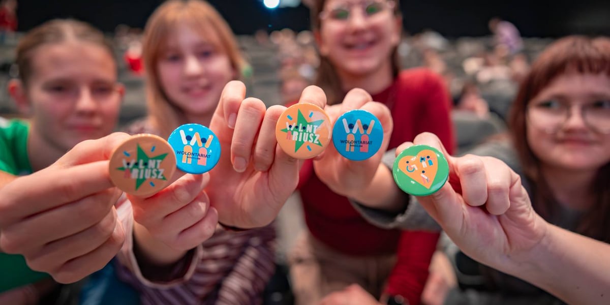 Młodzi wolontariusze pokazują przypinki w Nowych Horyzontach, 5 grudnia 2025