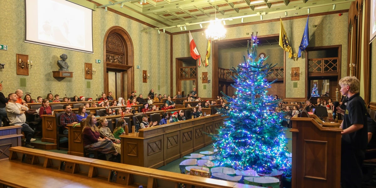 Choinka w sali sesyjnej, za nią duża grupa dzieci