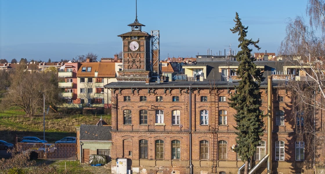 Widok na ceglany budynek z wieżą zegarową na terenie dawnej cukrowni na Klecinie (ul. Supińskiego)