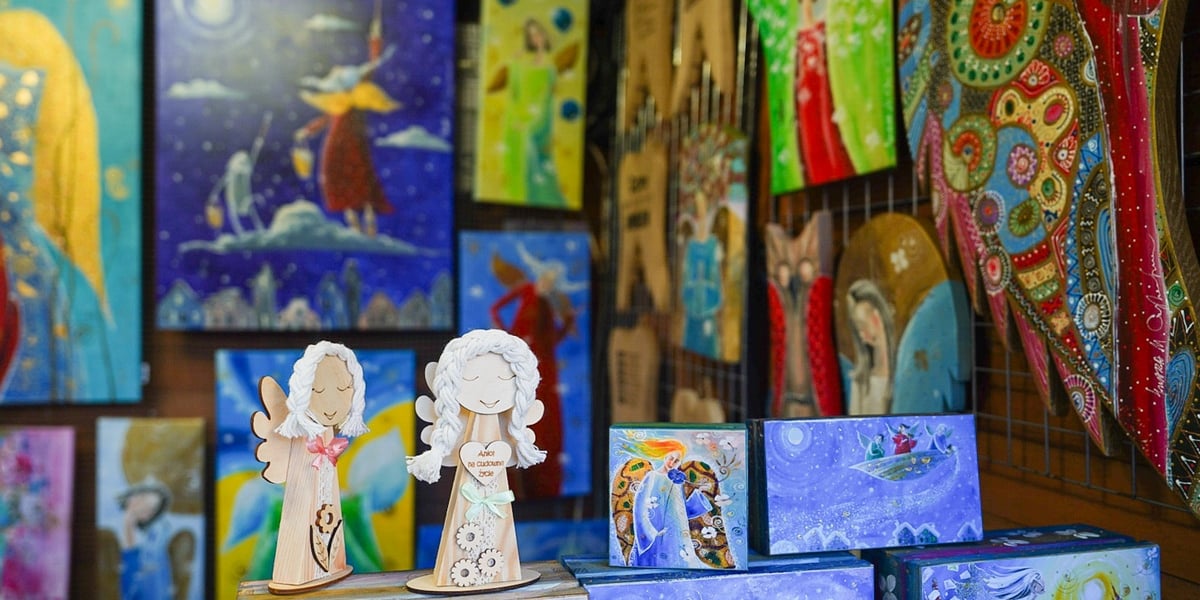 Stoisko na jarmarku bożonarodzeniowym. Zdjęcie ilustracyjne. Na zdjęciu ceramiczne aniołki i kolorowe obrazki