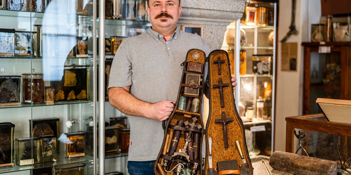 Dr Jędrzej Siuta z Zakładu Medycyny Sądowej UMW, opiekun Muzeum Medycyny Sądowej, prezentuje futerał z zestawem antywampirycznym. Na zdjęciu mężczyzna trzyma futerał, w którym znajdują się m.in. krucyfiksy, szklane butelki.