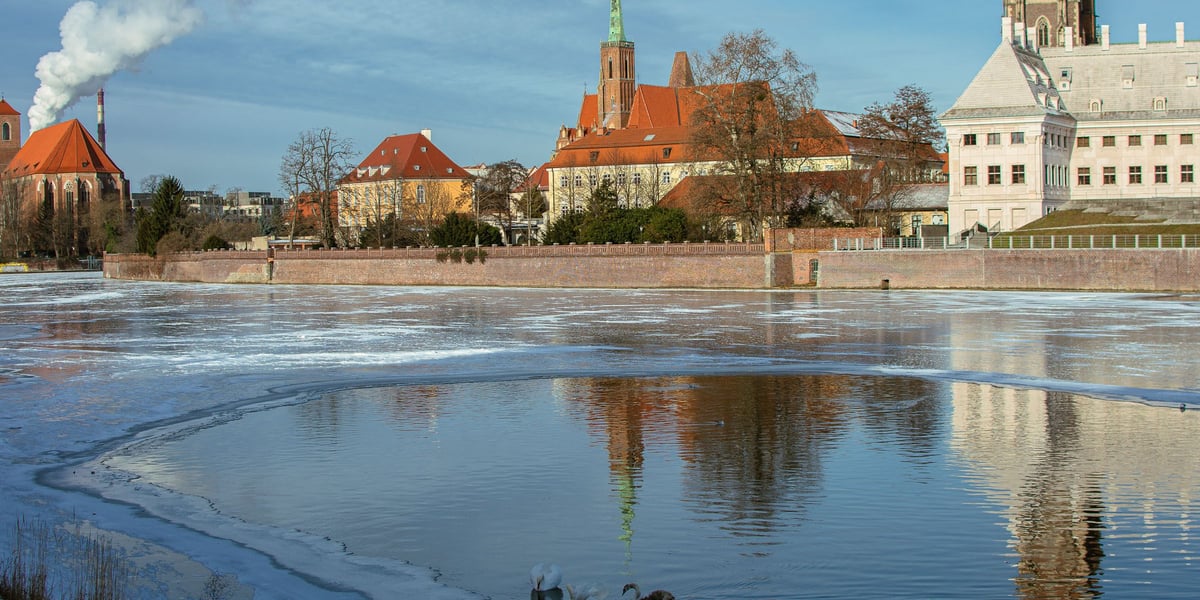 Na pierwszym planie rzeka Odra, częściowo zamarznięta. W tle widok Ostrowa Tumskiego.