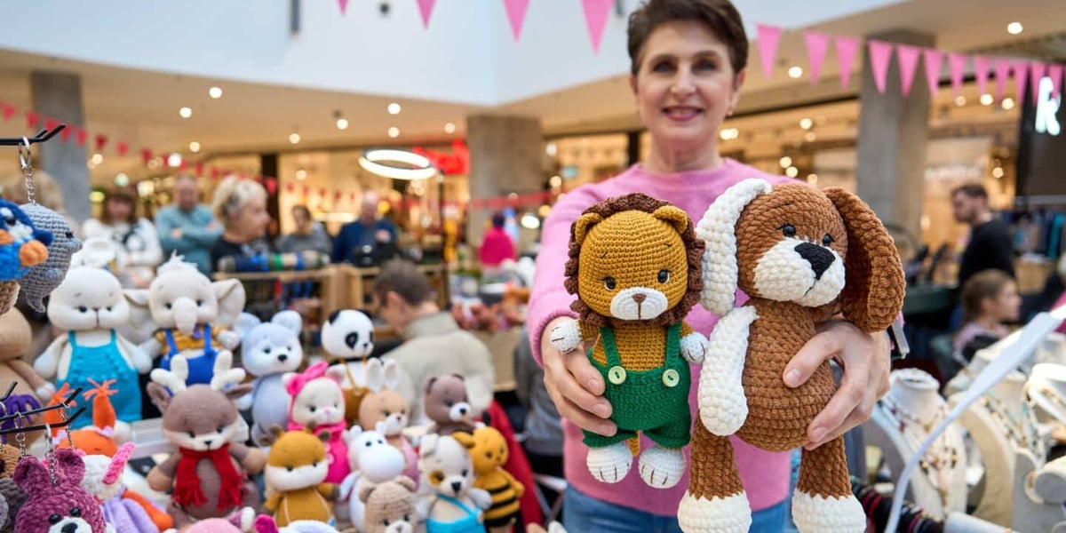 Uśmiechnięta kobieta prezentująca dwie szydełkowe maskotki, targi Artishop 17.01.2026 r.