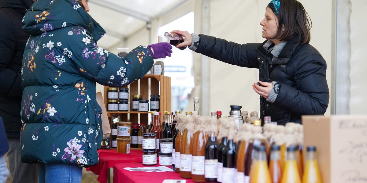 Dolnośląski Targ Rolny przy ul. Zwycięskiej. Wrocław, 24.01.2026. Na zdjęciu sprzedawczyni nalewająca klientce soku do kubeczka.
