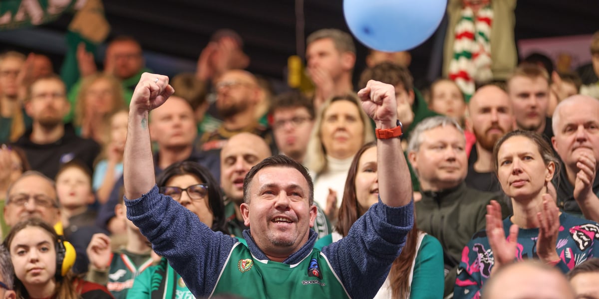 Mężczyzna wznoszący ręce do góry i inni kibice na trybunie Hali Orbita podczas meczu z Treflem Sopot