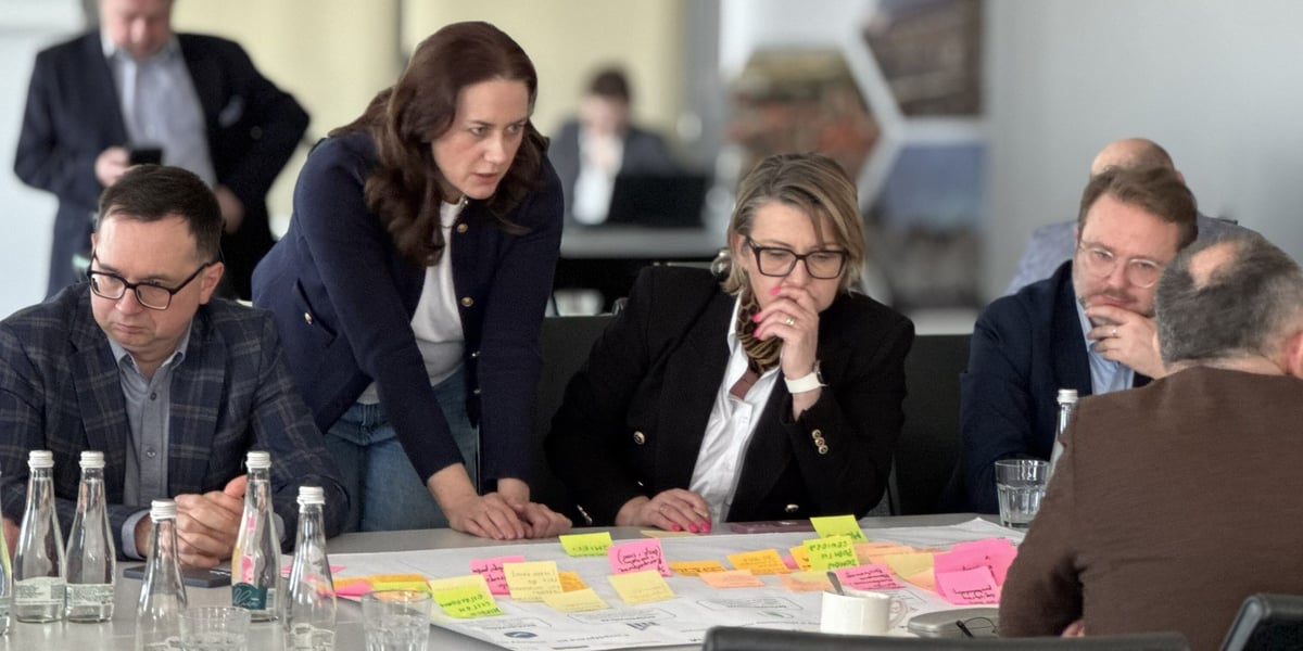 Warsztaty strategiczne Wrocławskiego Obszaru Metropolitalnego. Na zdjęciu grupa osób dyskutuje przy stole