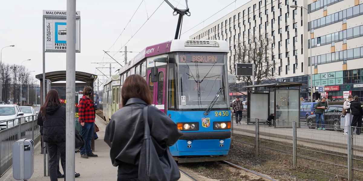 Ludzie stojący na przystanku "Małopanewska" i nadjeżdżający tramwaj po wznowieniu ruchu tramwajowego.