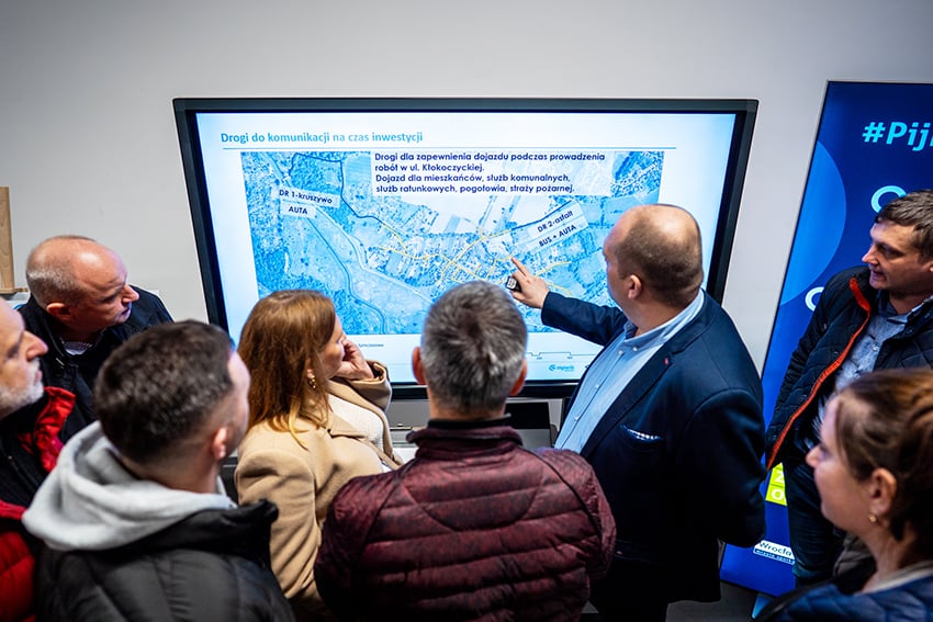 Spotkanie z mieszkańcami na Kłokoczycach ws. kanalizacji w roku 2024; kilka osób patrzy na ekran, na którym widać drogi komunikacji na czas inwestycji - zdjęcie ilustracyjne.