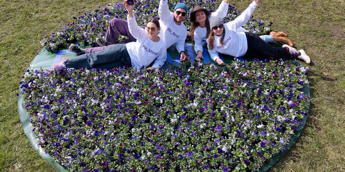 Ludzie leżą na trawie wśród kwiatów w doniczkach