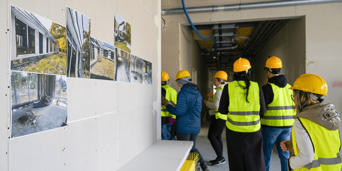Dzień otwarty Publicznego Przedszkola Dębinka na Sołtysowicach. Na zdjęciu grupa osób w kaskach i kamizelkach zwiedza plac budowy