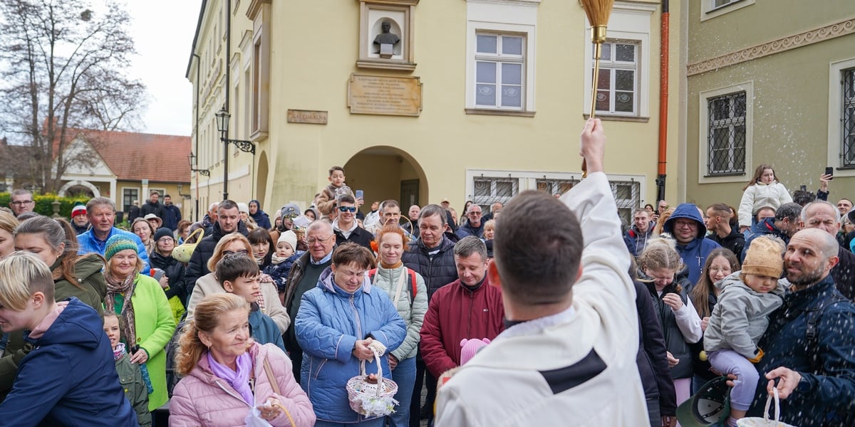 Święcenie pokarmów przed katedrą na Ostrowie Tumskim. Na zdjęciu ksiądz z kropidłem i ludzie z koszyczkami ze święconką