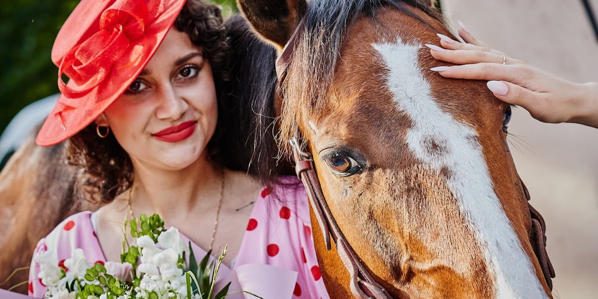 Wrocławski Tor Wyścigów Konnych. Na zdjęciu kobieta w sukience i kapeluszu przytula głowę konia