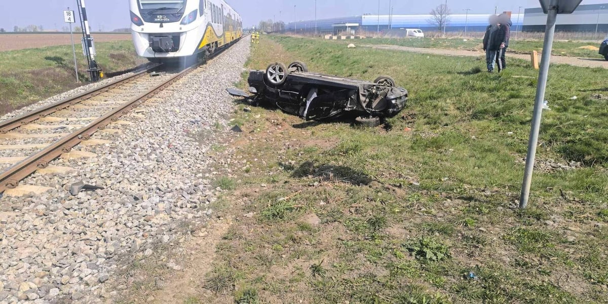 Zdjęcie przedstawiające rozbite auto leżące na dachu przy torach kolejowych i pociąg w tle - wypadek na przejeździe w Chrzanowie 11 kwietnia 2026 r.
