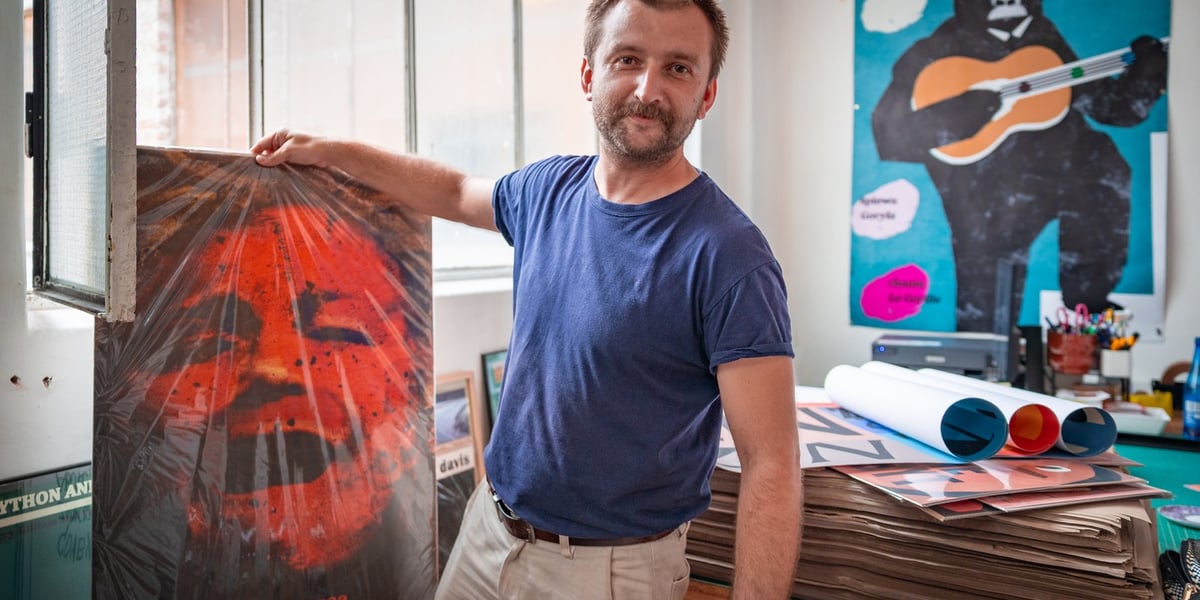 Na zdjęciu Jakub Zasada w swoim sklepie-pracowni z plakatem do filmu „Dzikość serca”, w tle jego plakat ukochany z Georges'em Brassensem 