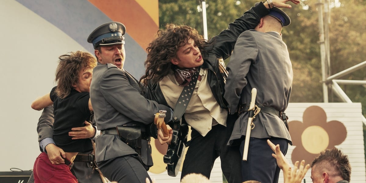Policjanci chwytający Jana Borysewicza na scenie, kadr z filmu „Mniej obcy”