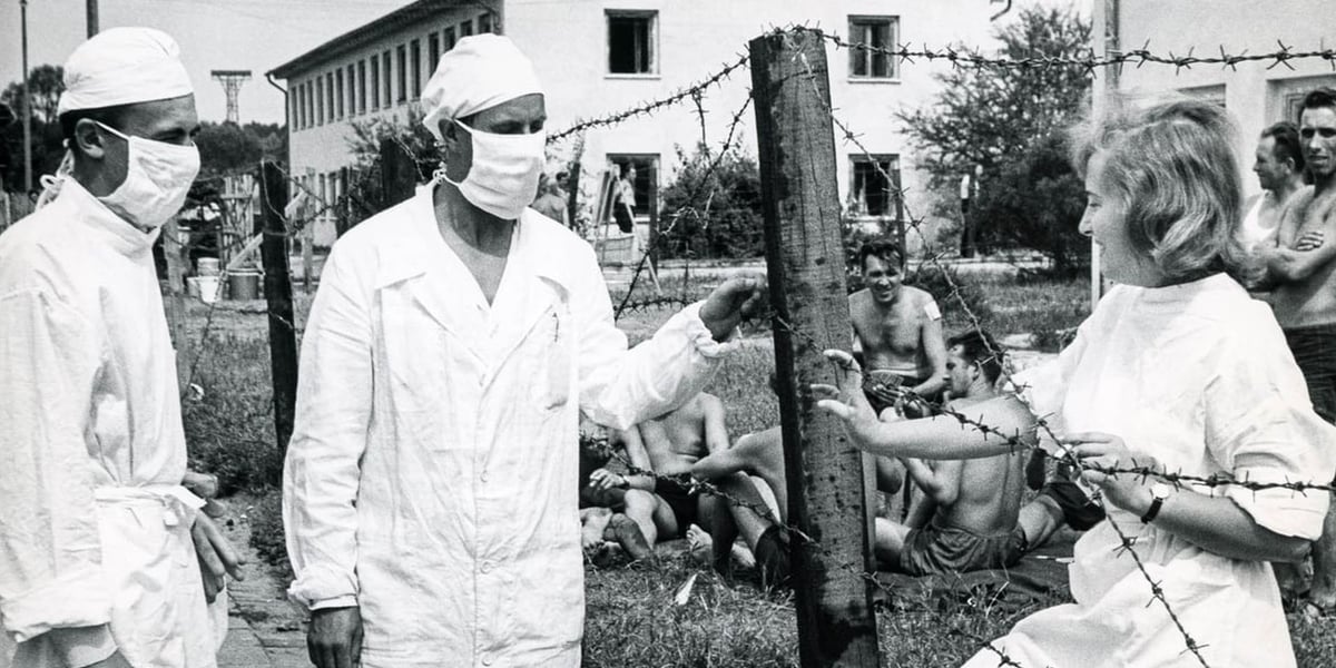Izolatorium na Psim Polu podczas epidemii czarnej ospy. Na pierwszym planie dwóch mężczyzn w białych uniformach i maseczkach, obok uśmiechnięta kobieta w białym fartuchu. Zdjęcie Mieczysława Dołęgi ze zbiorów Muzeum Miejskiego Wrocławia. 
