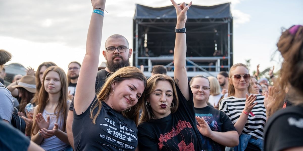 Kolaż dwóch zdjęć – na większym dziewczyna na koncercie trzymająca kartkę z napisem „Czy mogę kostkę do gitary?!?!”, na mniejszym tłum wrocławian na koncercie 3-Majówki
