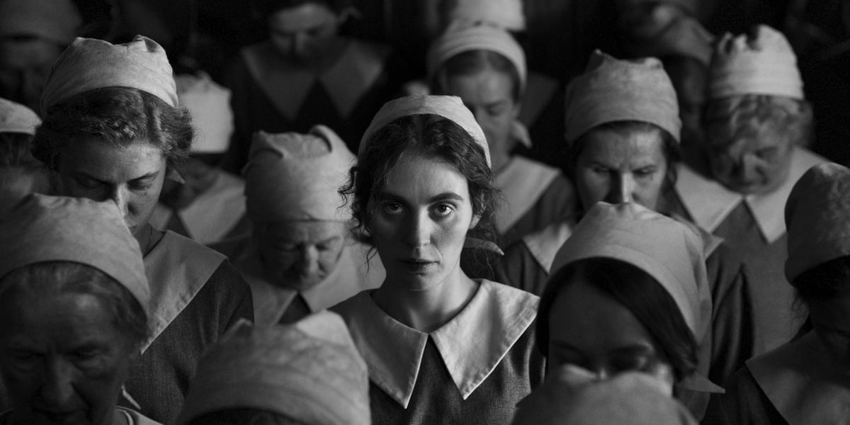 Czarno-biały kadr z filmu „Dziewczyna z igłą”. W środku aktorka Victoria Carmen Sonne