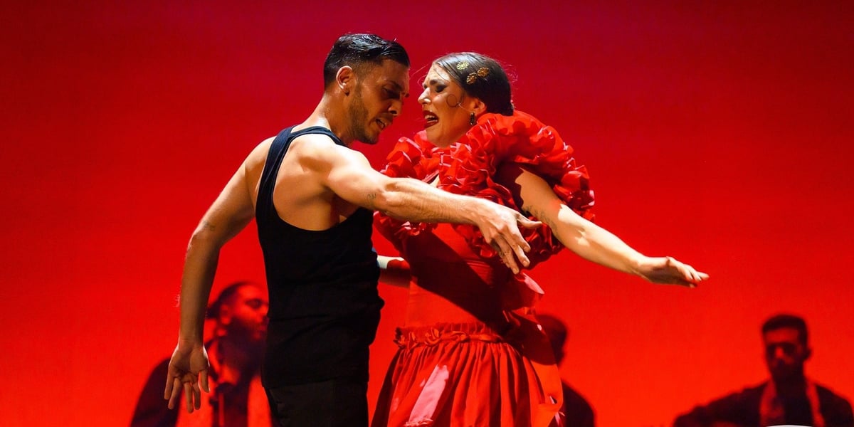 Kobieta w sukni czerwonej tańczy flamenco z mężczyzną ubranym w czarną koszulkę bez rękawów, spektakl Carmen w wykonaniu zespołu Barcelona Flamenco Ballet