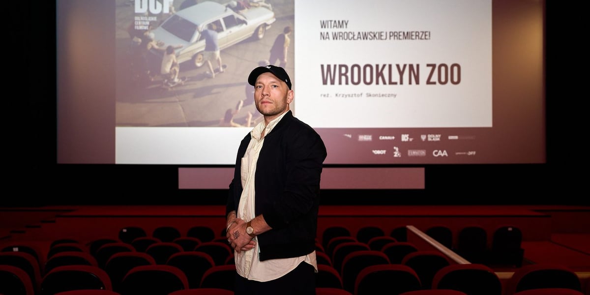 Na zdjęciu Krzysztof Skonieczny w sali kina DCF na tle ekranu, na którym wyświetlona jest zapowiedź filmu „Wrooklyn Zoo”