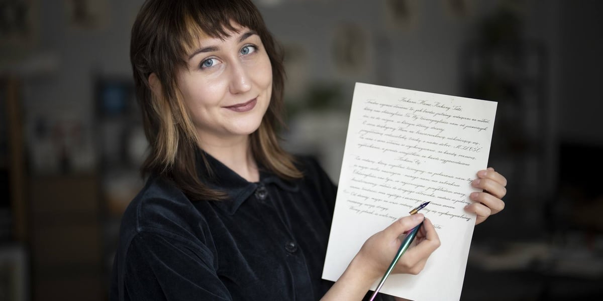 Uśmiechnięta Zuzanna Chróścik, trzymająca list i przyrząd do kaligrafii