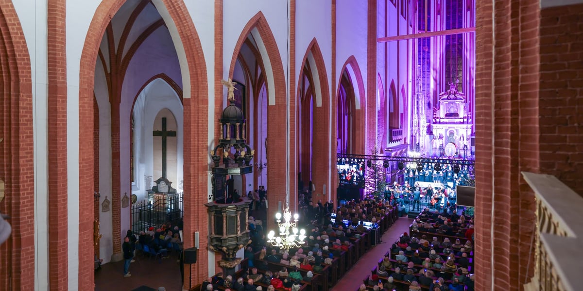 Wnętrze bazyliki św. Elżbiety, ludzie siedzący w ławach, artyści na scenie, rzut z góry