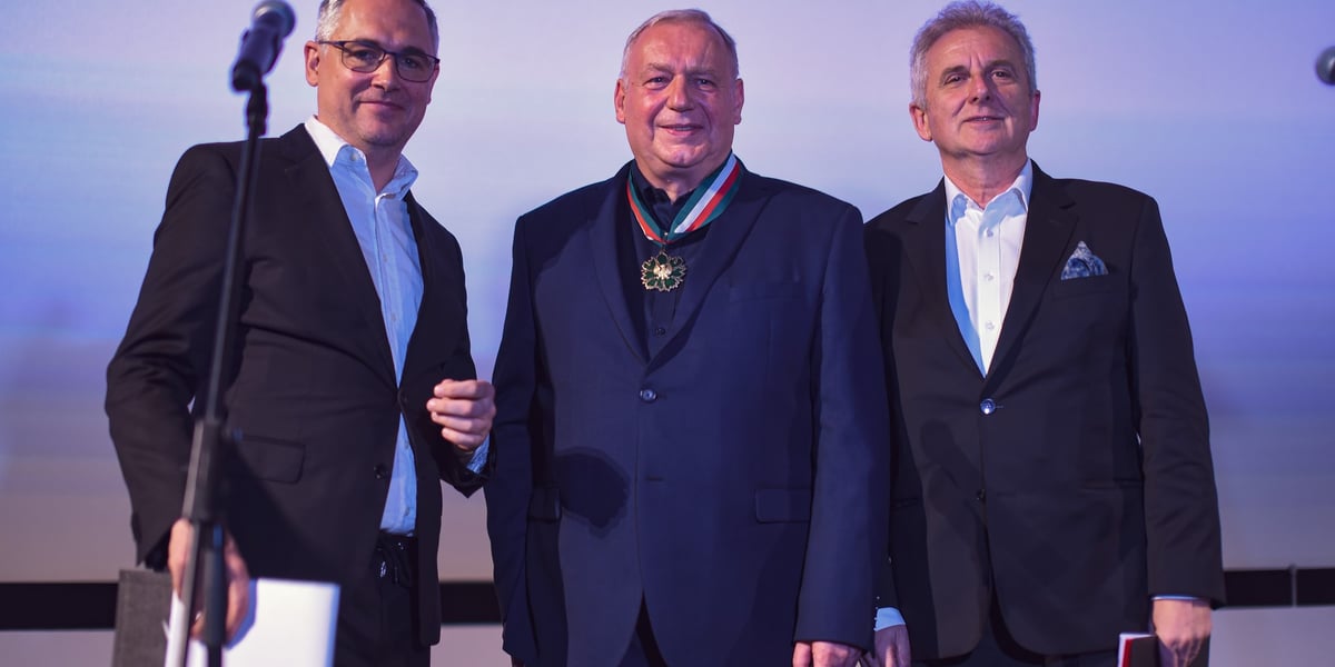 Trzech mężczyzn, w środku Roman Gutek z medalem Gloria Artis