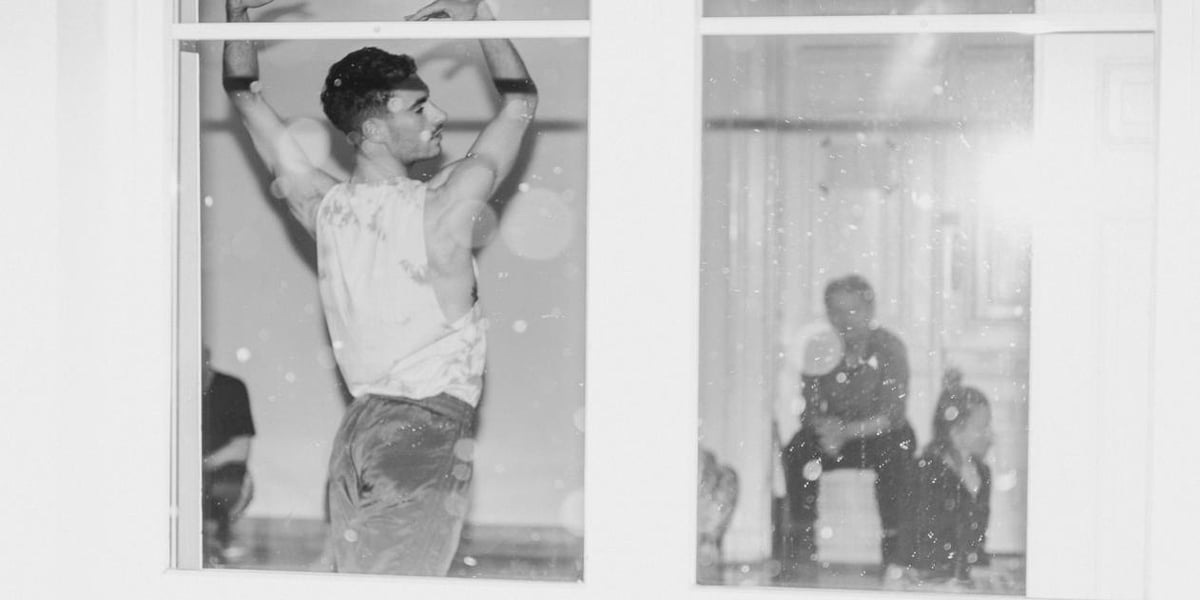 Mężczyzna w koszulce bez rękawów widziany przez okno, zdjęcie z próby do "Złych Baśni".