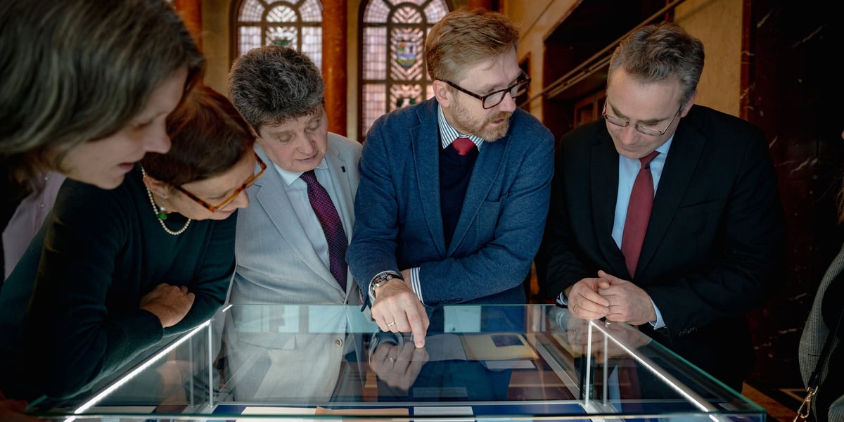 Grupa osób oglądająca eksponaty w gablocie. Wystawa  „Pojednanie dla Europy”  przygotowana przez Centrum Historii Zajezdnia w berlińskim ratuszu.