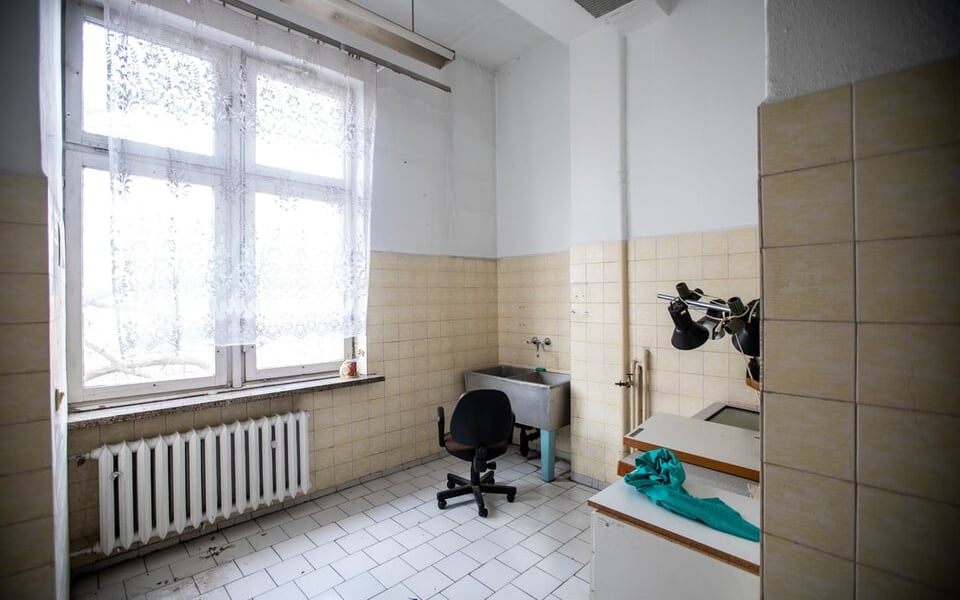 Czarne krzesło na kółkach w opuszczonym pomieszczeniu kliniki na Bujwida