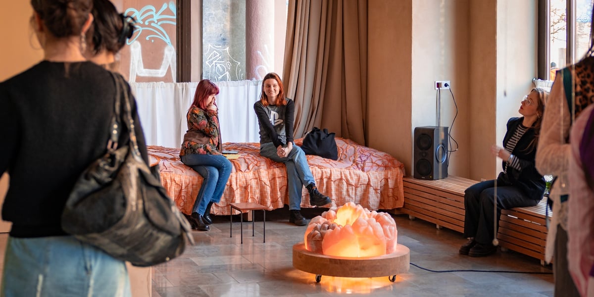 Kilka osób siedzących na ławce i łóżku artystycznym w sali głównej Żyjni