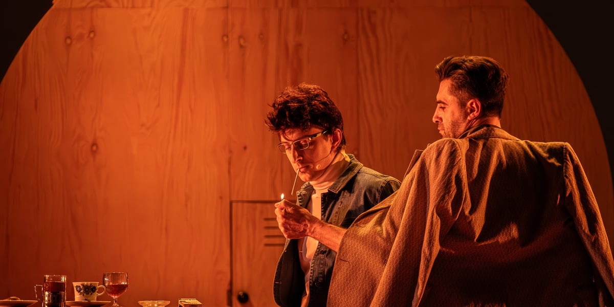 Lubiewo na scenie Wrocławskiego Teatru Współczesnego. Scena z próby spektaklu. Na zdjęciu dwóch mężczyzn, jeden przypala drugiemu papierosa