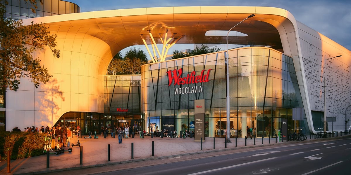 Wizualizacja przedstawiająca budynek centrum handlowego Wroclavia, na którym widnieje nowe logo: czerwony napis Westfield oraz biały dopisek Wroclavia
