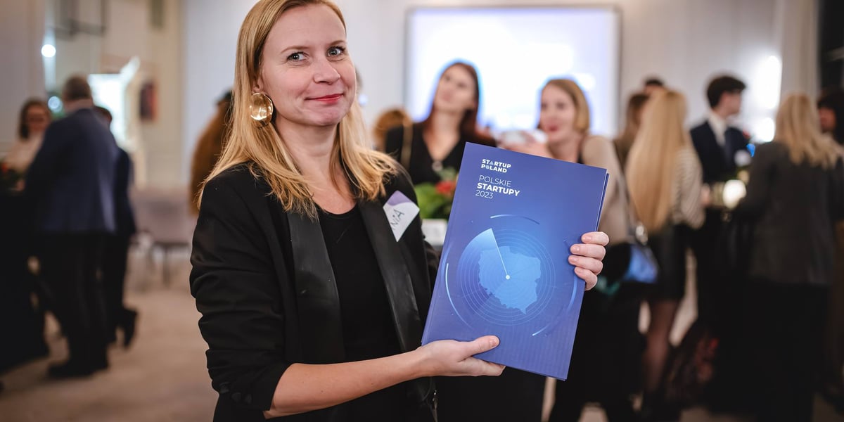 Kobieta trzymająca raport "Polskie Startupy 2023".