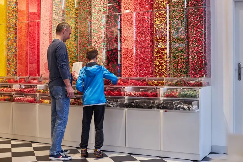 Na zdjęciu:  mężczyzna i chłopiec przed ścianą z cukierkami w nowym sklepie Sweet Factory Store we Wrocławiu
