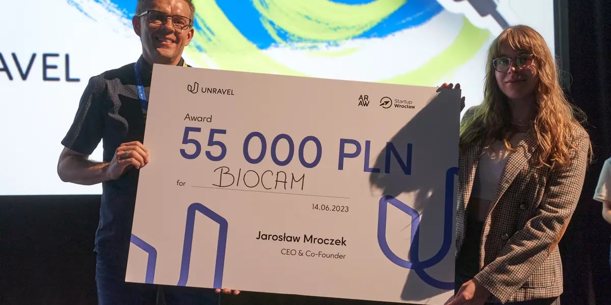 Zwycięzcy konkursu startupów z firmy BioCam na scenie w Kinie Nowe Horyzonty. Od lewej mężczyzna w okularach i kobieta trzymają białą planszę z kwotą 55 tys. PLN