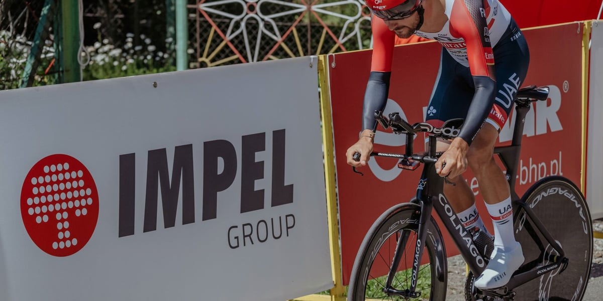 Kolarz na trasie Tour de Pologne. W tle baner z napisem "Impel Group"