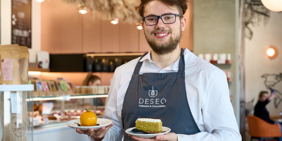 Nataniel, menadżer cukierni DESEO z ciastkami na talerzykach