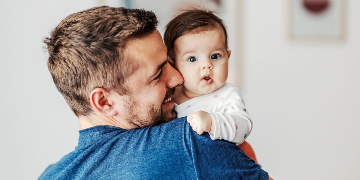 Młody mężczyzna trzyma dziecko na rękach, zdjęcie ilustracyjne. Pracujący rodzice dostaną z ZUS 1500 zł co miesiąc