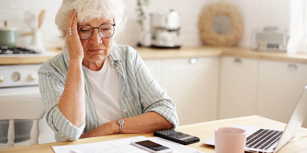Starsza kobieta siedzi przy stole, patrzy na dokumenty, zdjęcie ilustracyjne. ZUS zamyka ePUAP dla klientów. Są nowe zasady korespondencji