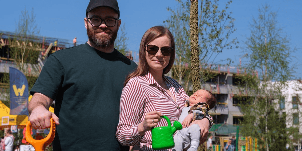 Piknik WROśnij we WROcław na skwerze Scharouna na osiedlu Leśnica - 18 kwietnia 2026 r. para z dziećmi pozuje do zdjęcia przy drzewku 