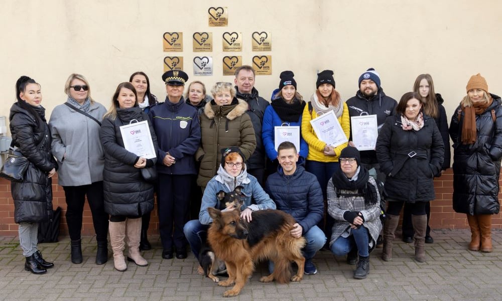 „Rodzinna” fotografia na tle ściany trybuny na partynickim torze, obrastającej nowymi tabliczkami, to miła tradycja Wrocławskiego Serca dla Zwierząt  