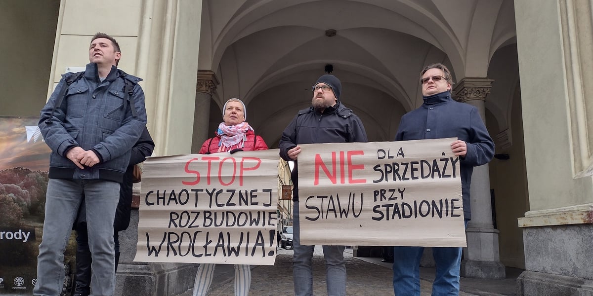 Na zdjęciu: czwórka osób protestujących z dwoma transparentami pod ratuszem