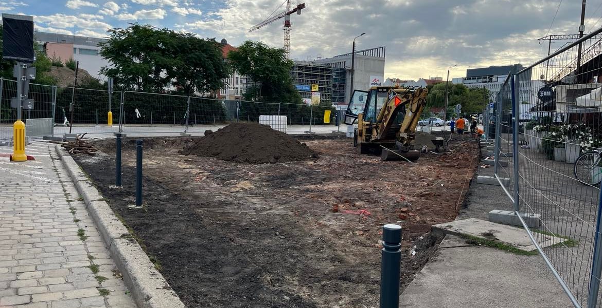 Zrywają asfalt pod nasypem. Na zdjęciu fragment szerokiego chodnika ze zdjętym asfaltem. Na drugim planie koparka.