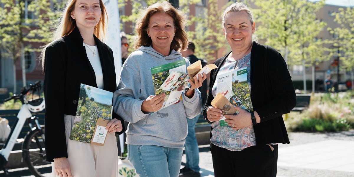 Trzy uśmiechnięte kobiety z paczkami z nasionami pszczelego pożytku