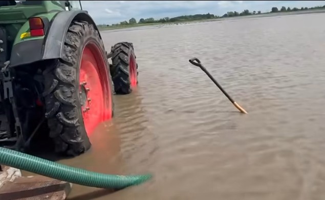 Kadr z filmu pokazujący ciągnik stojący na polu zalanym wodą