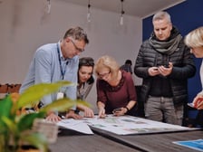 Przykład spotkania konsultacyjnego. Dyskutujący uczestnicy pochyleni nad koncepcją zagospodarowania podwórka.