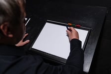 <p>Z wizytą w Niewidzialnym Domu we Wrocławiu. Na zdjęciu mężczyzna z kredką nad kartką papieru.</p>